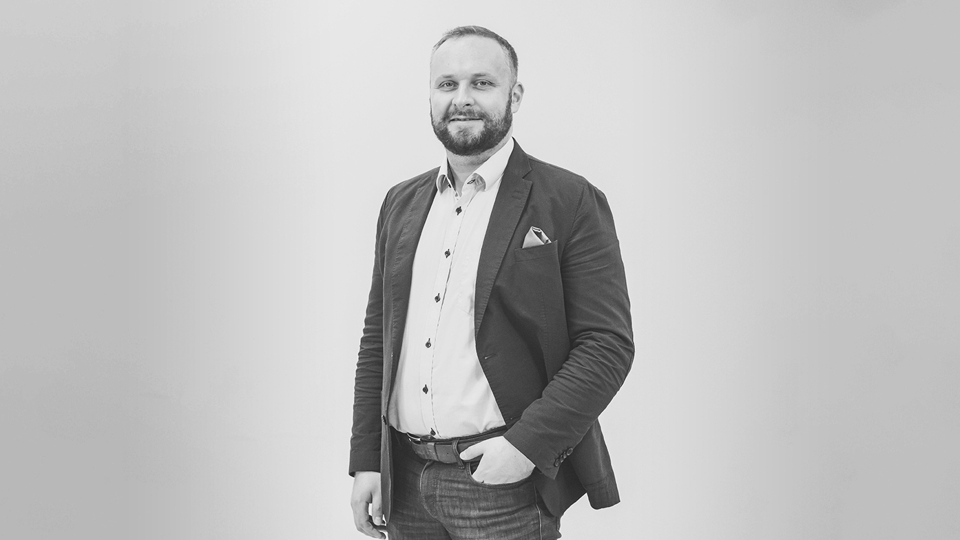 Mies studiokuvassa, katsoo kameraan.