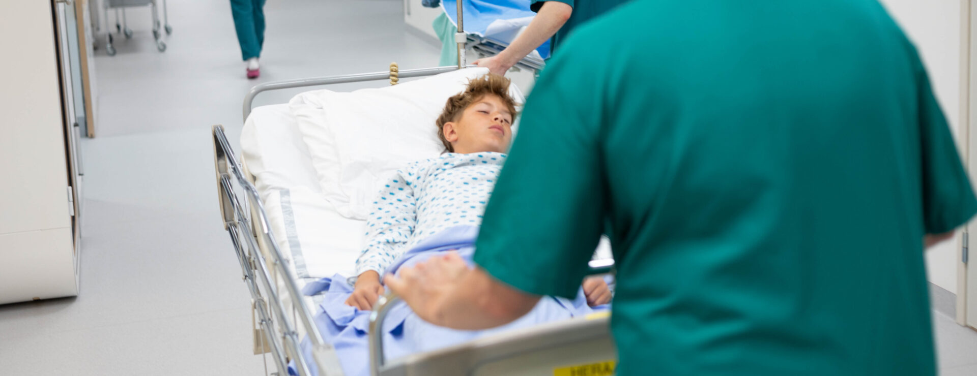 Nuorta potilasta kuljetetaan sairaalasängyssä sairaalan käytävällä.