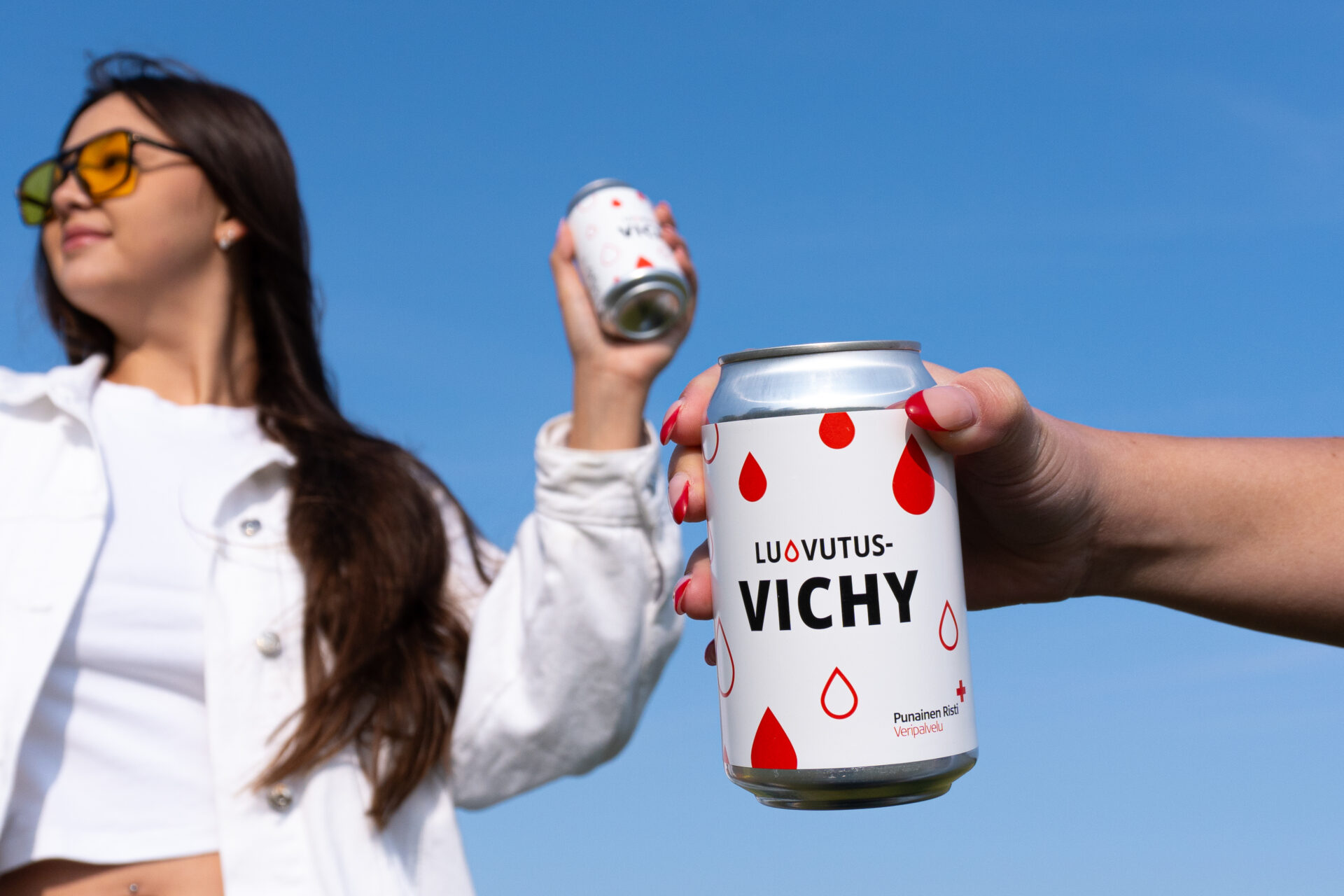 Kaksi nuorta naista pitelee Veripalvelun kesäjuomia kädessään ulkona.