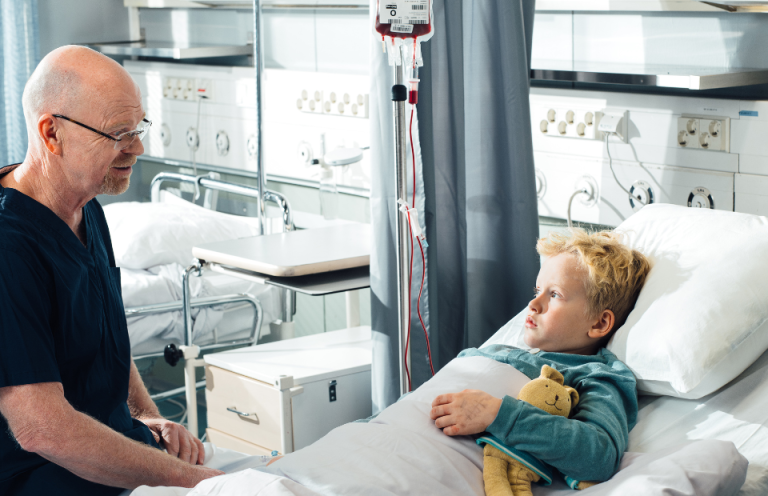 Pieni potilas, jonka vierellä istuu hoitaja