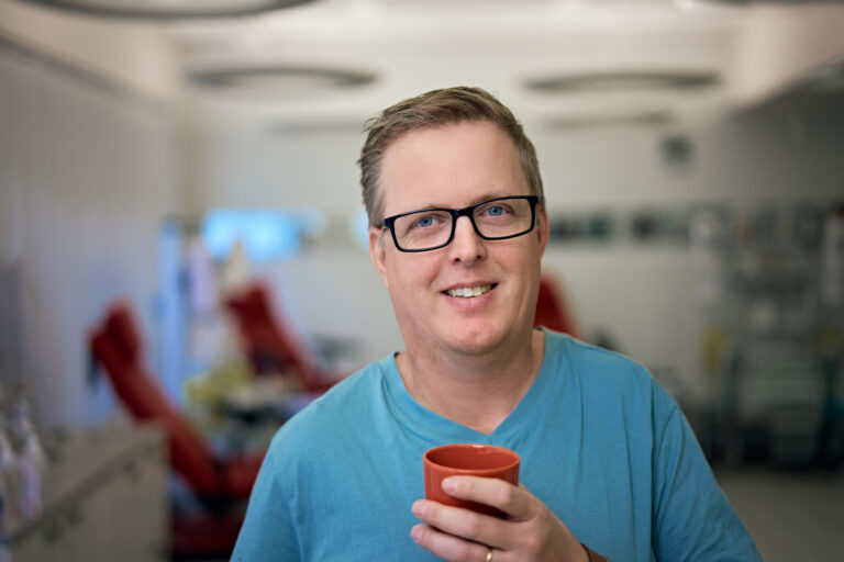 Miesverenluovuttajalla punainen muki kädessä.