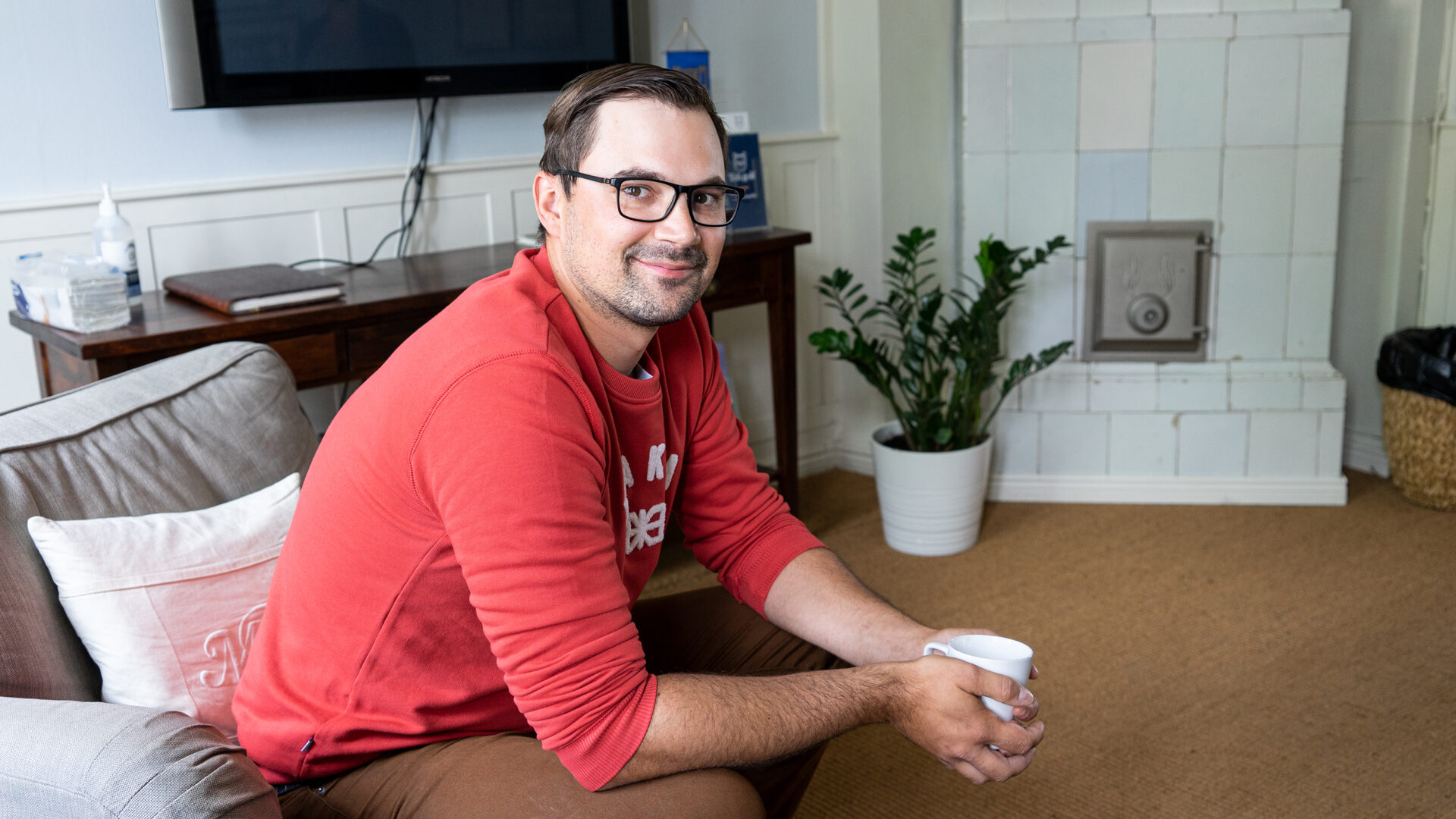 Stem cell donor Roberto Battilana sitting on a sofa with a cup coffee.