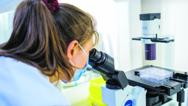 A scientist looks through a microscope.