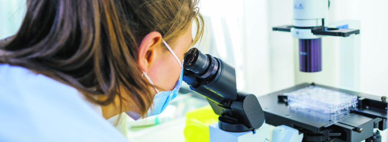 A scientist looking into a microscope.