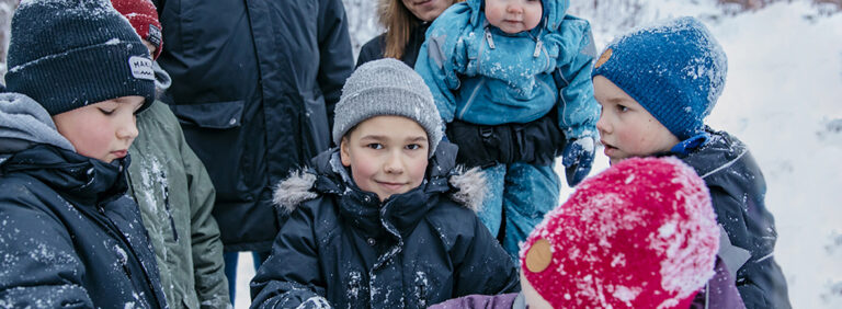 Kahdeksanhenkinen Hyryn perhe leikkimässä ulkona talvella.