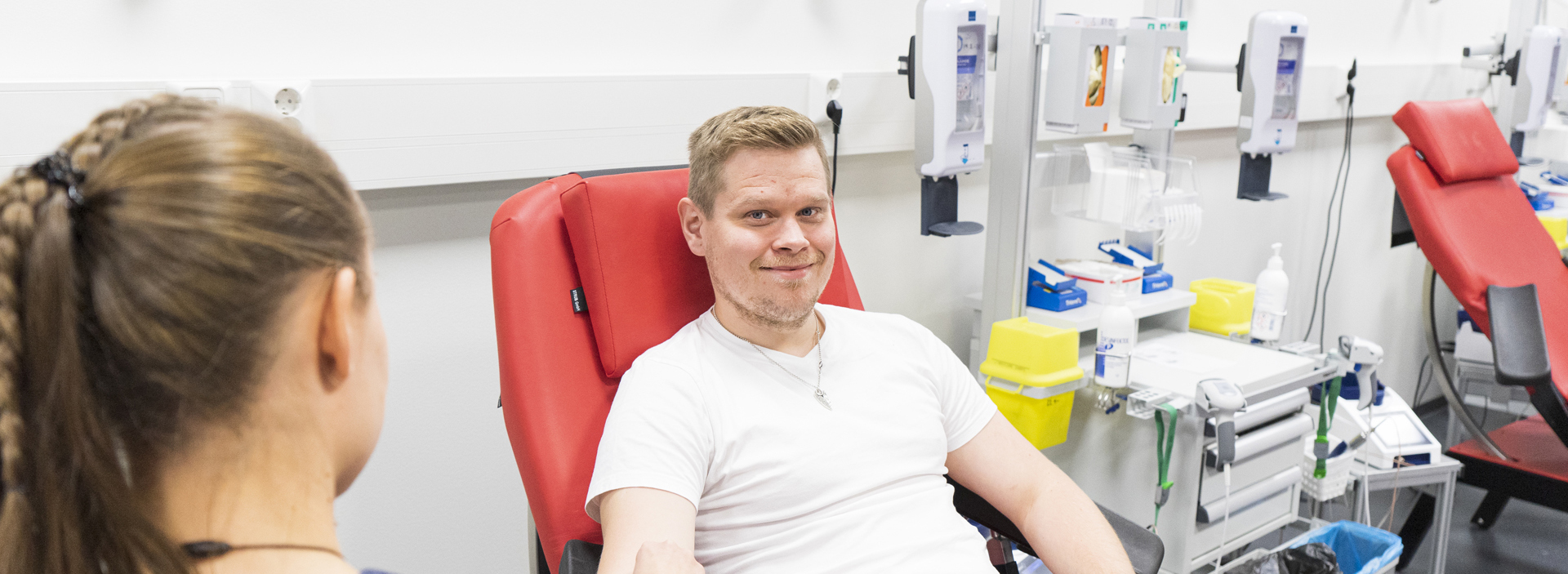 A man sitting at blood donation and smiling to the camera.