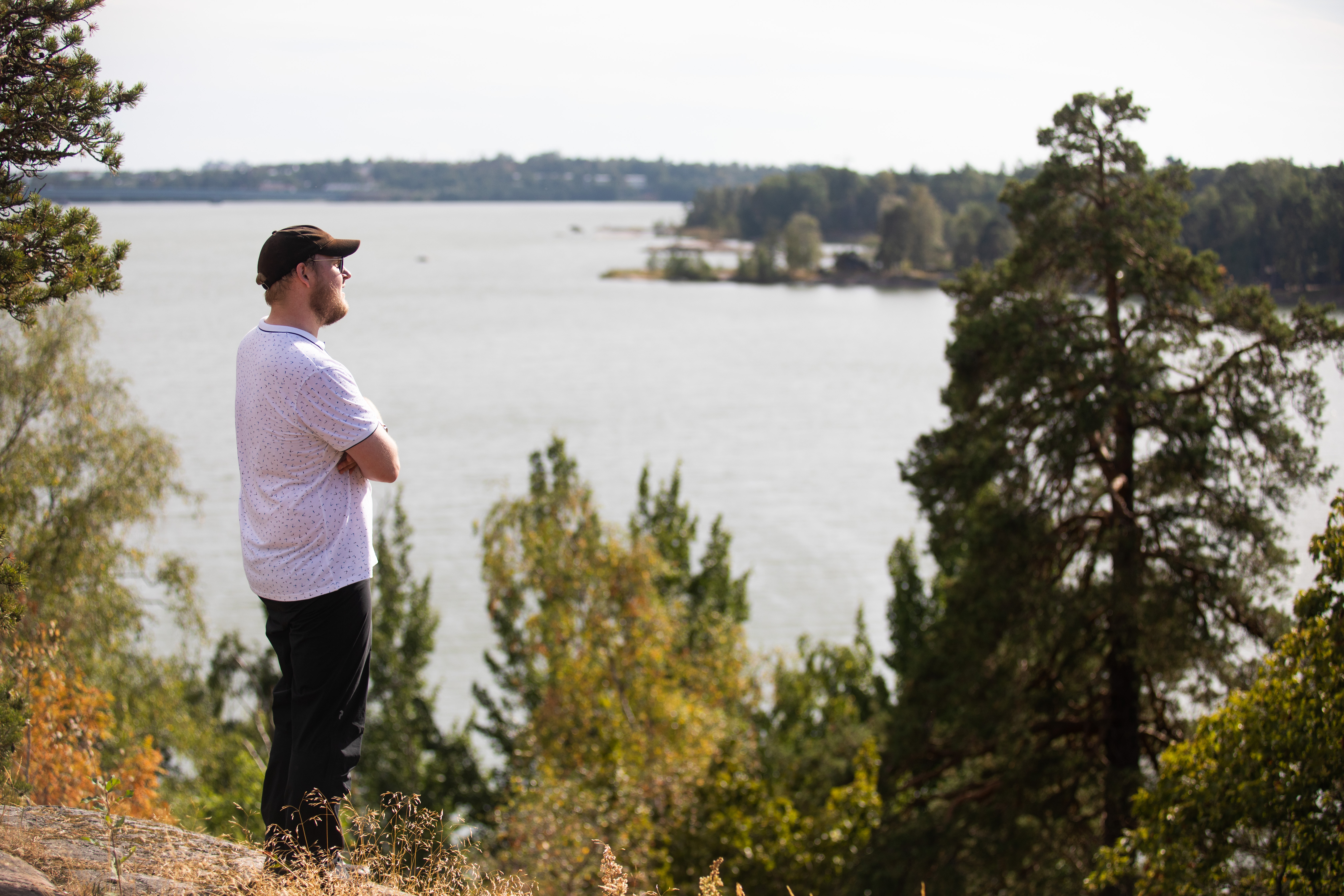 En man botad från lymfkörtelcancer tittar i fjärran på en sten vid vattnet.