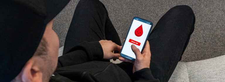En man som bokar tid för att donera blod på en mobiltelefon.