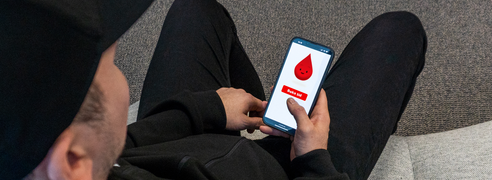 En man som bokar tid för att donera blod på en mobiltelefon.