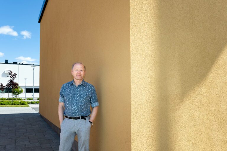Ylilääkäri Matti Korhonen katsoo kohti kameraa keltainen seinä taustallaan.