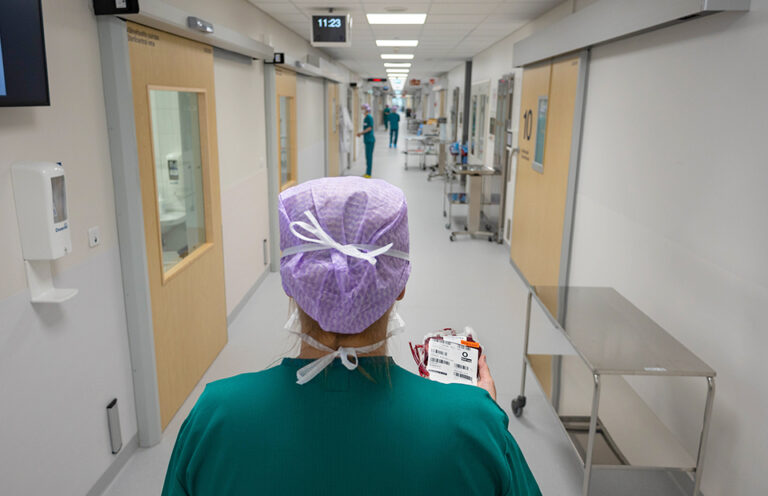 Terveydenhuollon ammattilainen kantaa punasoluvalmistetta sairaalan käytävällä.