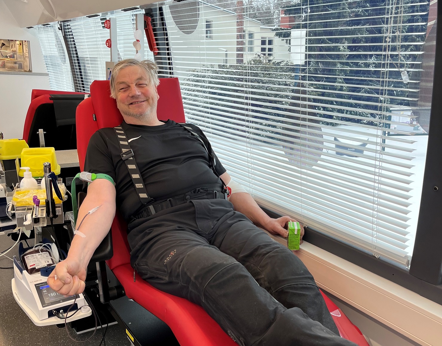 Verenluovuttaja Raimo Ryhtä luovuttaa iloisena verta Verenluovutusbussissa.