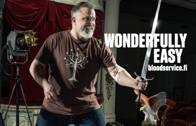 Actor Kristo Salminen stage-fights with a sword and has a blood donation bandage on his elbow. The text in the picture reads: Wonderfully easy, veripalvelu.fi.